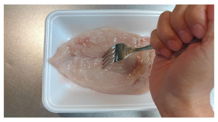 鶏むね肉をフォークで刺す写真